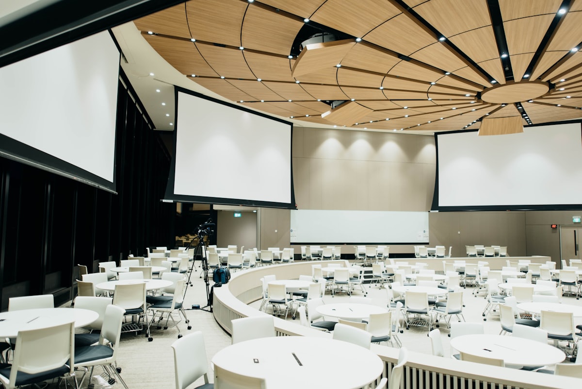 An empty conference room set with round tables and projection screens