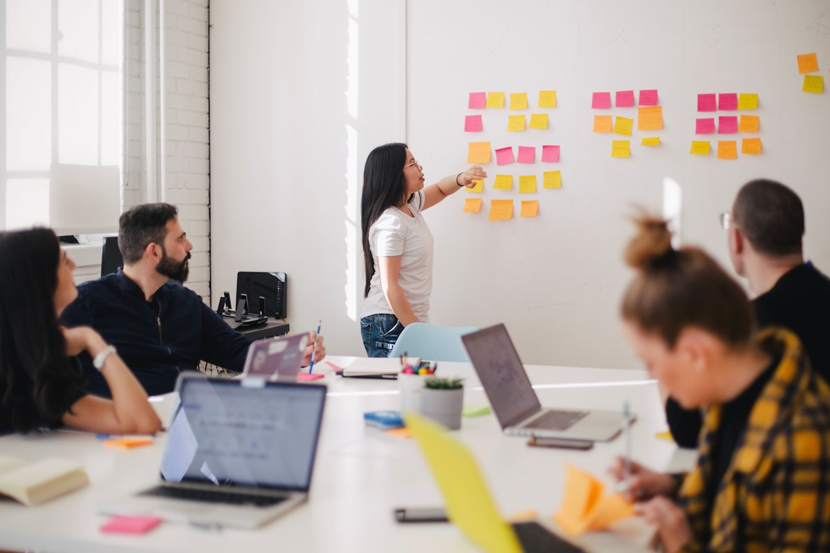 A team at a table working through a wall of sticky notes